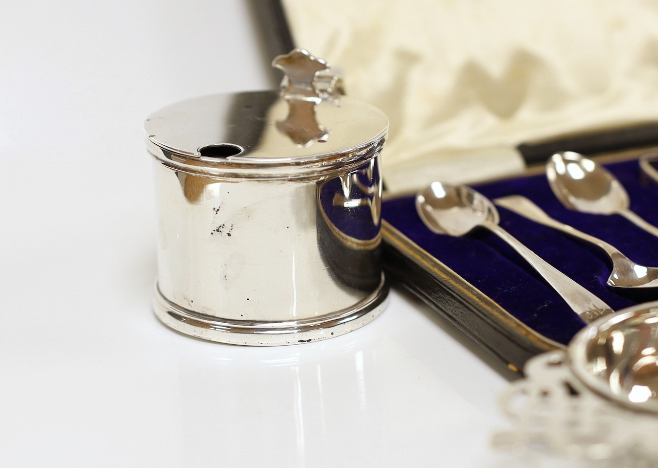 Small silver including a mounted inkwell, tea strainer on stand, mustard pot, small dish and cased set of six coffee spoons with sugar tongs.